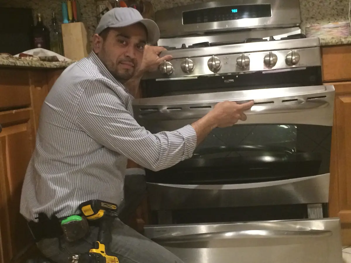 Eddie's Appliance Repair technician checking a stainless steel double-oven range in a customer's kitchen
